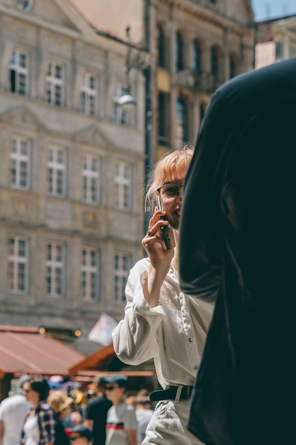 Szemüveges ember vintage flip telefonon beszél a belvárosban.